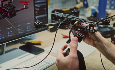 Drone held up to monitor with 3D design of drone